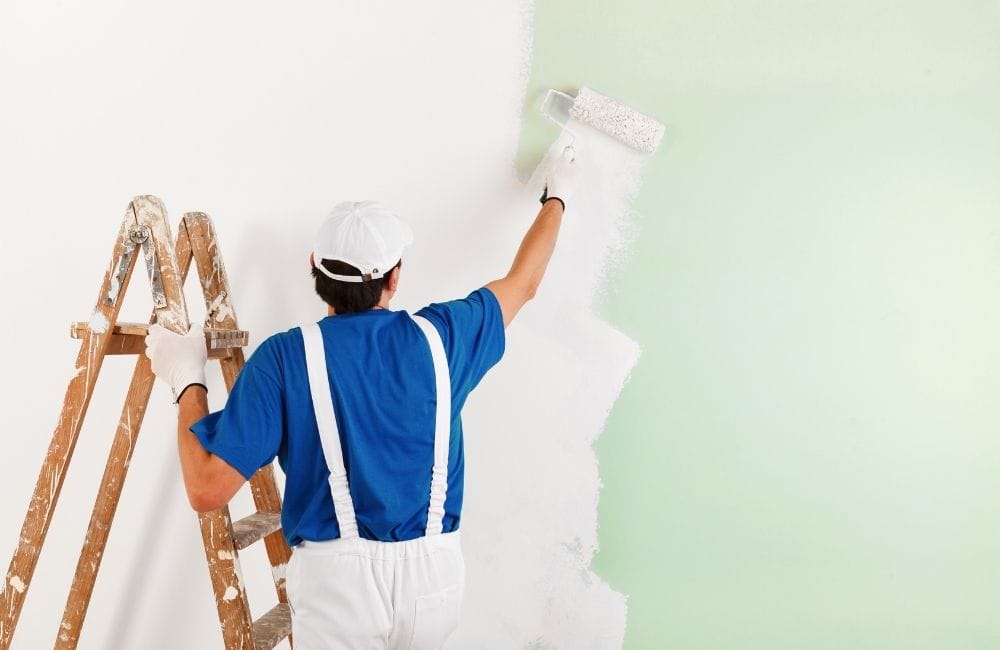 Contractor painting wall with green paint