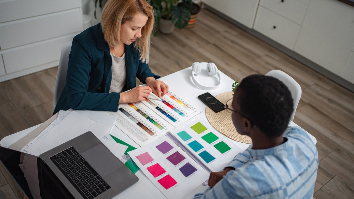 Two people sit at a table reviewing various colorful design palettes
