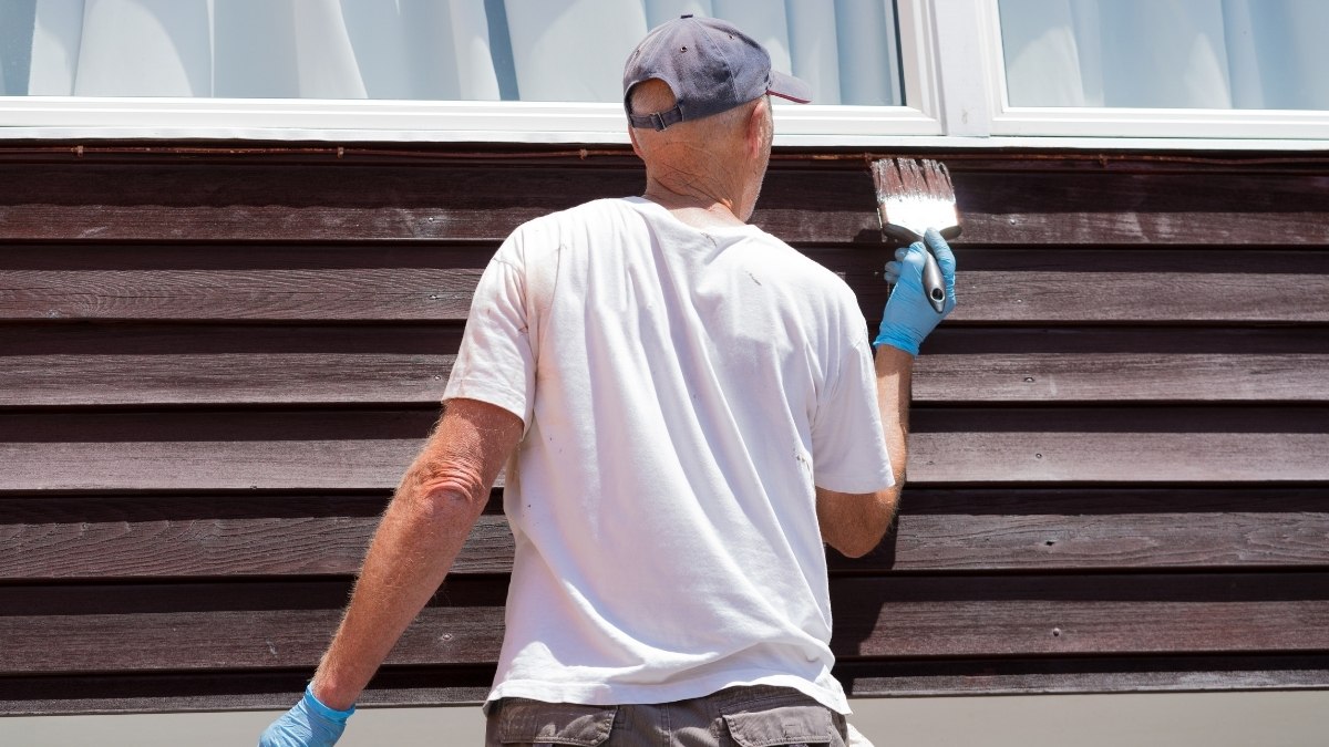 individual applying a dark finish with a paintbrush