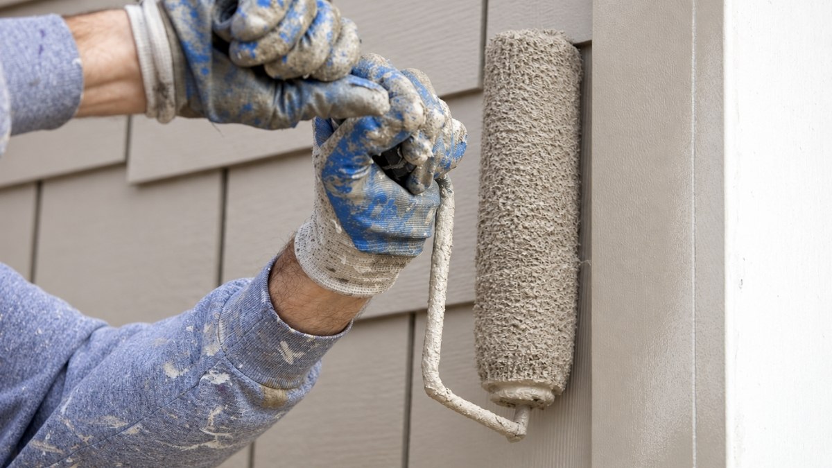 close-up of a worker wearing paint-splattered blue and white gloves